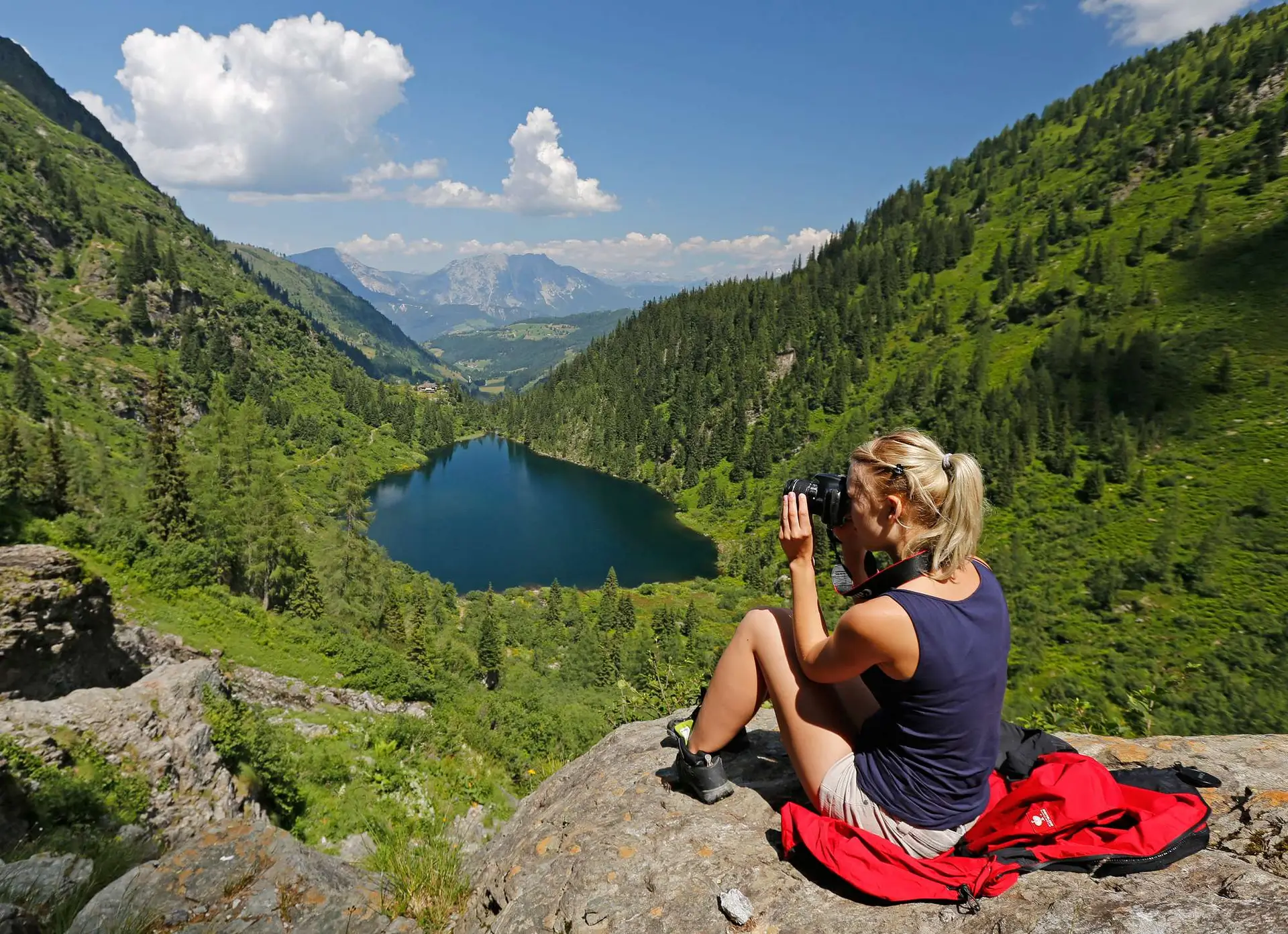 Eine Frau fotografiert einen See in Ramsau am Dachstein, einer wunderschönen Bergregion, die zum Wandern beliebt ist.